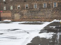 a parking lot with snow covered roads and windows in front of a brick building in the snow