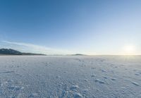 a snowy plain under a clear blue sky with some snow on the ground and sun above