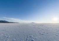 a snowy plain under a clear blue sky with some snow on the ground and sun above