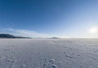 a snowy plain under a clear blue sky with some snow on the ground and sun above