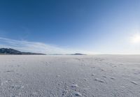 a snowy plain under a clear blue sky with some snow on the ground and sun above