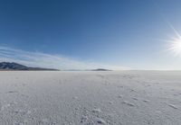 a snowy plain under a clear blue sky with some snow on the ground and sun above