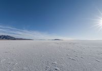 a snowy plain under a clear blue sky with some snow on the ground and sun above