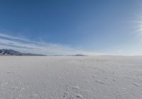 a snowy plain under a clear blue sky with some snow on the ground and sun above