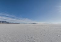 a snowy plain under a clear blue sky with some snow on the ground and sun above