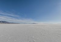 a snowy plain under a clear blue sky with some snow on the ground and sun above