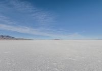 a snowy plain under a clear blue sky with some snow on the ground and sun above