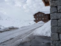 the snow covers the road and walkway to a house on top of the mountain side