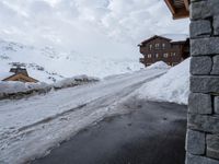 the snow covers the road and walkway to a house on top of the mountain side