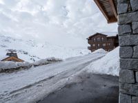 the snow covers the road and walkway to a house on top of the mountain side