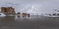 several buildings sit along the side of a snowy road on top of a hill covered in snow