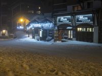 a hotel during the night in a snowy resort area at night with snowflakes on the sidewalk