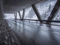 the road goes over the snow and rocks at the edge of the bridge in a snowstorm