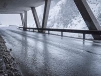 the road goes over the snow and rocks at the edge of the bridge in a snowstorm