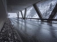 the road goes over the snow and rocks at the edge of the bridge in a snowstorm