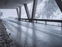 the road goes over the snow and rocks at the edge of the bridge in a snowstorm