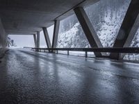 the road goes over the snow and rocks at the edge of the bridge in a snowstorm