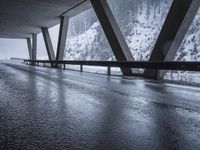 the road goes over the snow and rocks at the edge of the bridge in a snowstorm