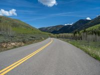 the road is paved with yellow markings and has a snowy mountain range in the background