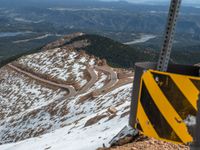 an empty road and a hill overlook the view of mountains and clouds and blue sky