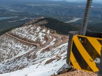 an empty road and a hill overlook the view of mountains and clouds and blue sky