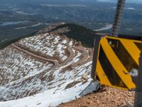 an empty road and a hill overlook the view of mountains and clouds and blue sky