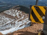 an empty road and a hill overlook the view of mountains and clouds and blue sky