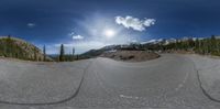 there is a panorama lens of the empty road in the mountains and hills with snow on the slopes