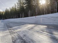 a long country road is covered with snow and has a person riding a ski on it