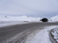 a car is parked in front of the snowy tunnel at the intersection of an empty road