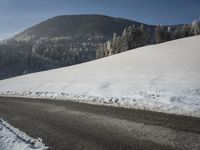 a snowy road in front of a snowy mountain range near the mountains covered with snow