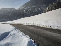 a snowy road in front of a snowy mountain range near the mountains covered with snow