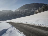 a snowy road in front of a snowy mountain range near the mountains covered with snow