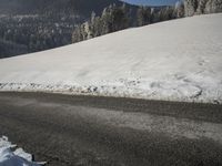 a snowy road in front of a snowy mountain range near the mountains covered with snow