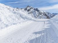 a person walks down a snowy road towards a mountain with a speed limit sign in front