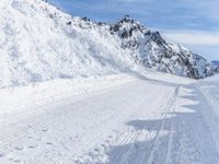 a person walks down a snowy road towards a mountain with a speed limit sign in front