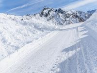 a person walks down a snowy road towards a mountain with a speed limit sign in front