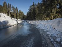 a car sits parked on the side of a snowy road, in the middle of a forested area
