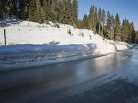 a car sits parked on the side of a snowy road, in the middle of a forested area