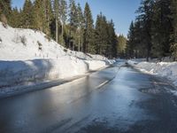 a car sits parked on the side of a snowy road, in the middle of a forested area