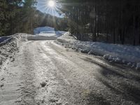 this road is covered in lots of snow and has the sun rising behind it and the skiier on top