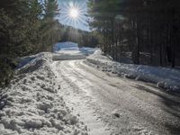 this road is covered in lots of snow and has the sun rising behind it and the skiier on top