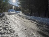 this road is covered in lots of snow and has the sun rising behind it and the skiier on top