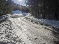 this road is covered in lots of snow and has the sun rising behind it and the skiier on top