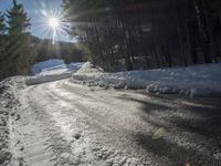 this road is covered in lots of snow and has the sun rising behind it and the skiier on top