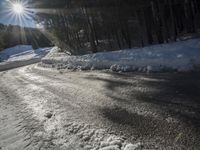 this road is covered in lots of snow and has the sun rising behind it and the skiier on top