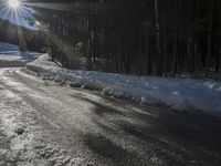 this road is covered in lots of snow and has the sun rising behind it and the skiier on top