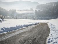 an image of a road with snow on the sides and a mountains in the background