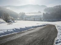 an image of a road with snow on the sides and a mountains in the background