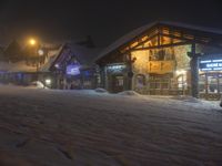 a man walks out to the lodge in a snowy night with snow piled on the ground